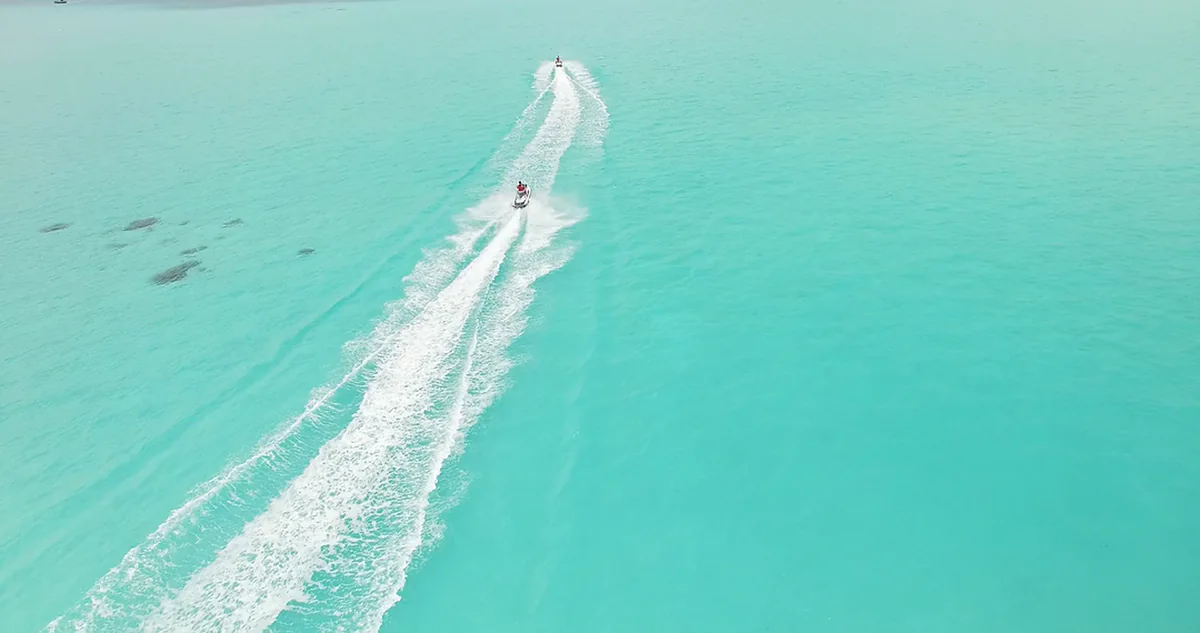 A vessel underway across a shallow lagoon, seen from the air